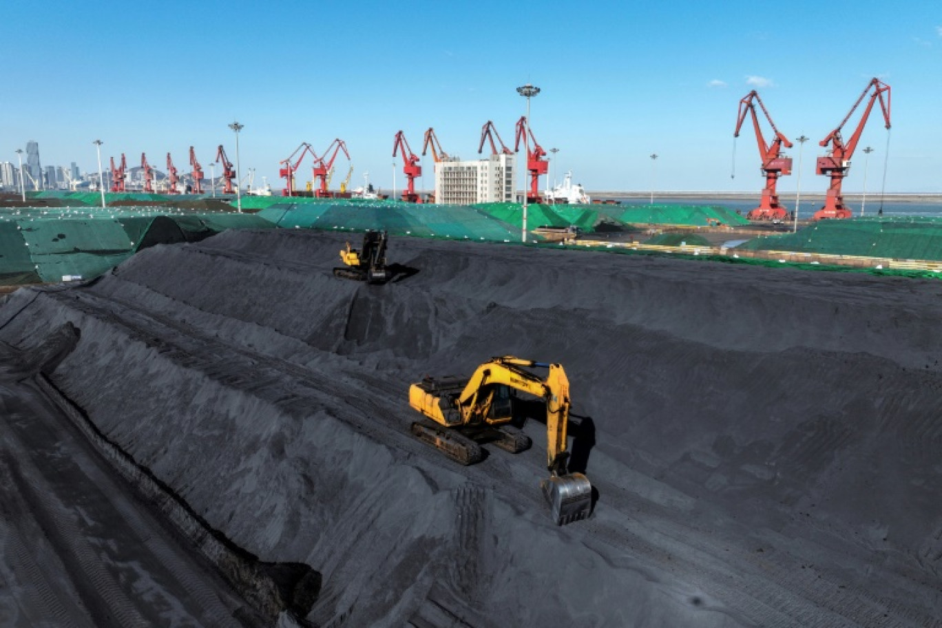 Des pelleteuses transfèrent du charbon au terminal du port de Lianyungang à Lianyungang, dans la province chinoise du Jiangsu, le 22 janvier 2024 © STR