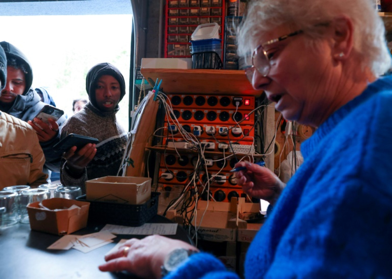 Brigitte Lips, surnommée "Mamie Charge" enregistre les téléphones des migrants pour les recharger dans son garage de Calais le 26 novembre 2024 © Denis Charlet