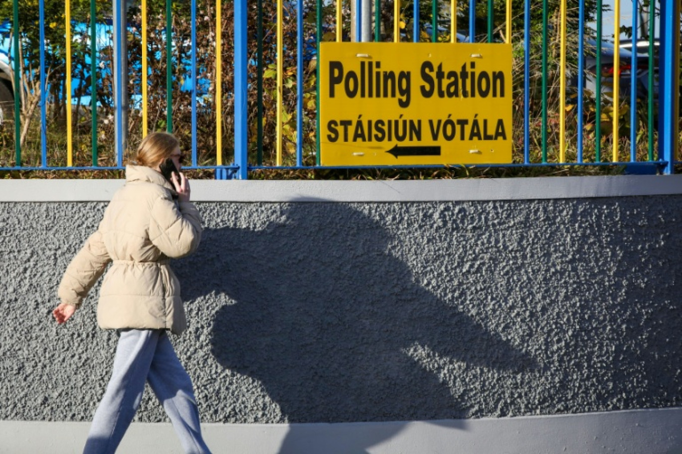 Une femme passe devant un panneau indiquant la direction d'un bureau de vote à Dublin le 25 novembre 2024, avant les élections législatives du 29 novembre © PAUL FAITH