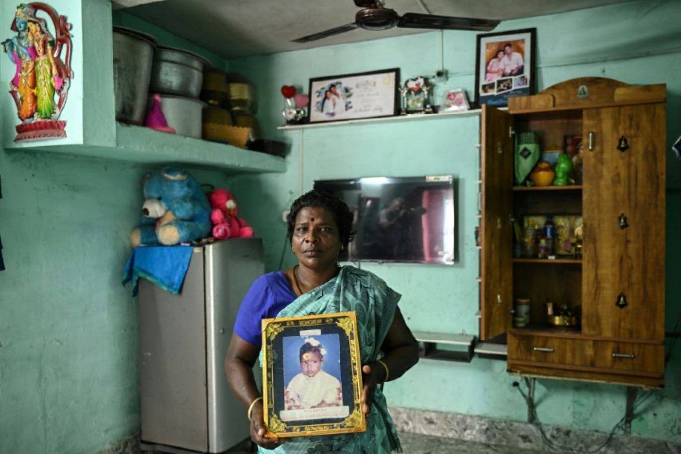 M Lakshmi,  victime du tsunami de 2004, montre un portrait de sa fille Yashoda, morte dans la catastrophe, lors d'une interview avec l'AFP dans une colonie résidentielle construite pour les victimes du tsunami à Nagapattinam, le 7 novembre 2024 dans l'État du Tamil Nadu, en Inde © R. Satish BABU