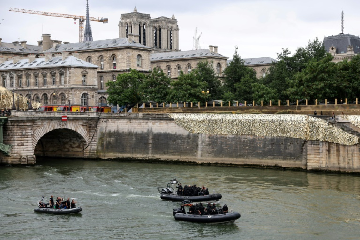 Des policiers du Raid patrouillent sur la Seine près de la cathédrale Notre-Dame de Paris avant la cérémonie d'ouverture des Jeux olympiques à Paris le 26 juillet 2024 © Jack GUEZ