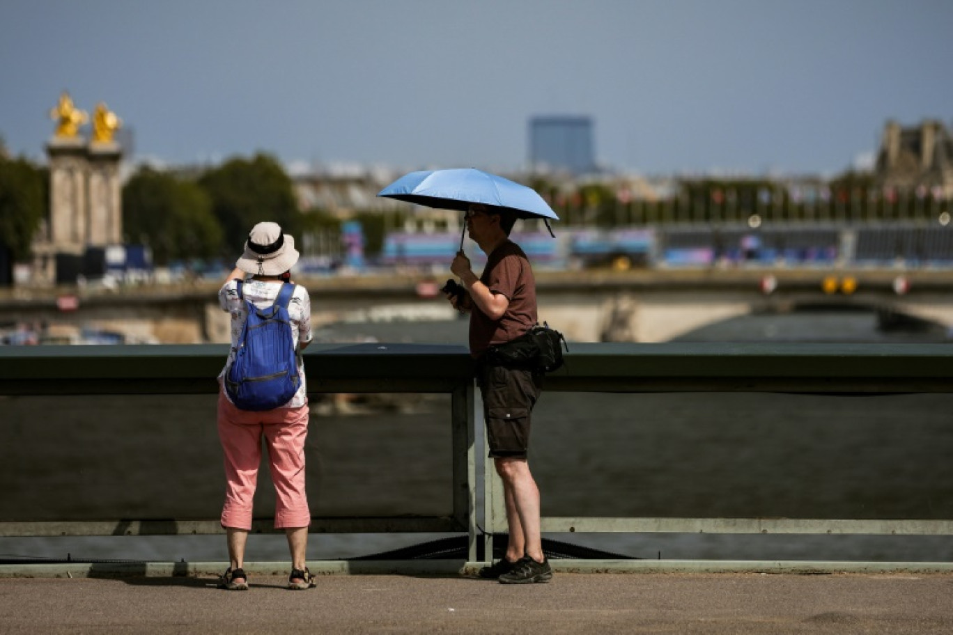 Un homme se protège du soleil avec un parapluie le 30 juillet 2024 à Paris © Thibaud MORITZ