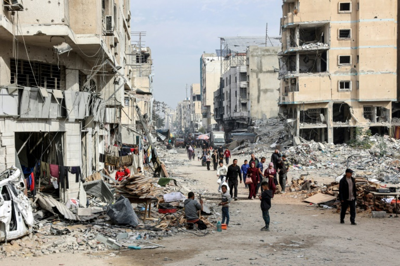 Des personnes marchent devant les décombres de bâtiments effondrés et endommagés dans une rue de la ville de Gaza, le 11 décembre 2024 © Omar AL-QATTAA