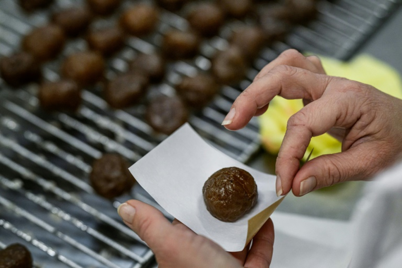 Une employée enveloppe un marron glacé dans les ateliers de l'entreprise Clément Faugier à Privas, en Ardèche, le 18 décembre 2024 © JEFF PACHOUD