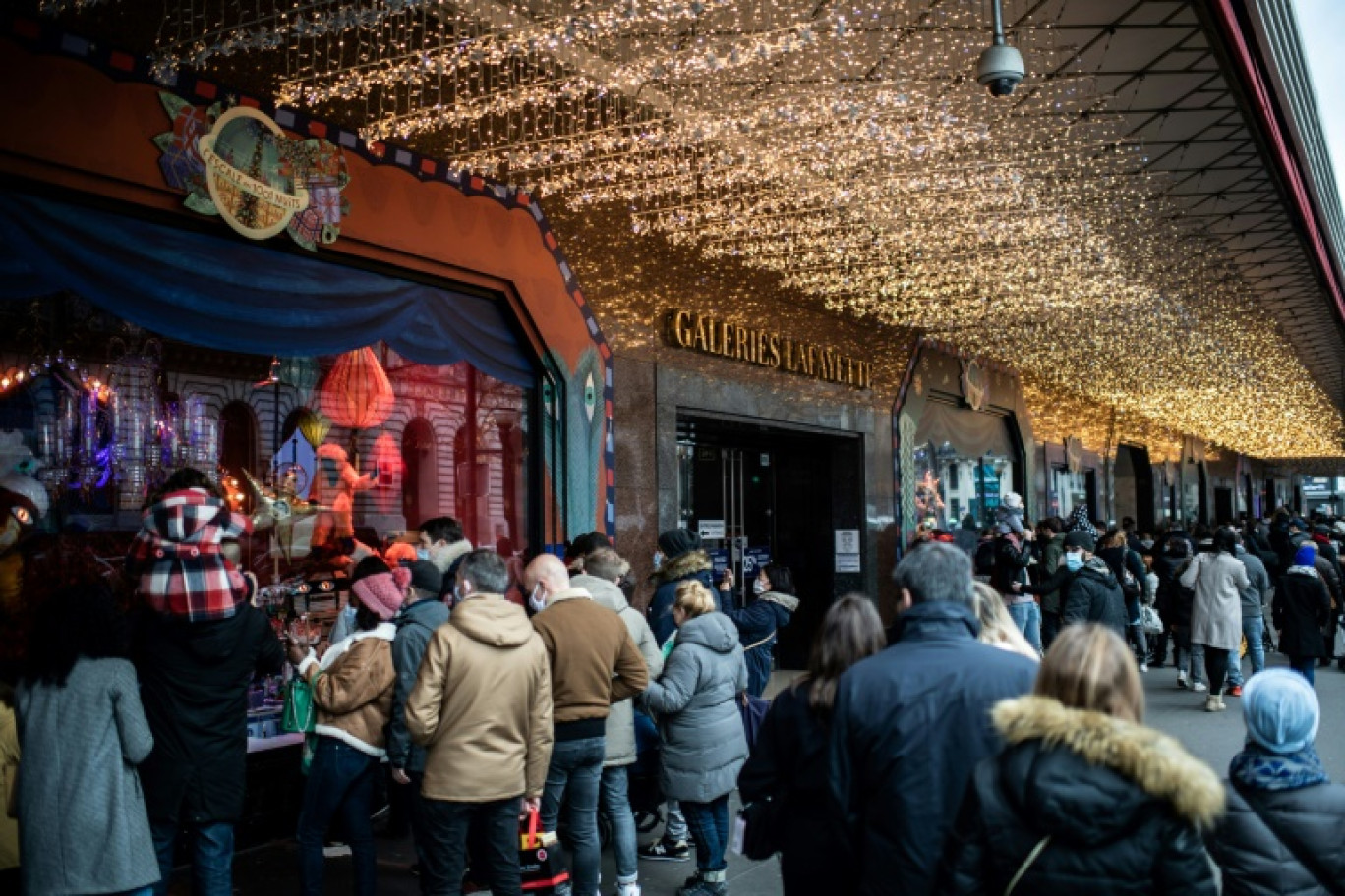 Des passants se pressent devant les vitrines de grands magasins, à Paris, le 20 décembre 2020 © Martin BUREAU