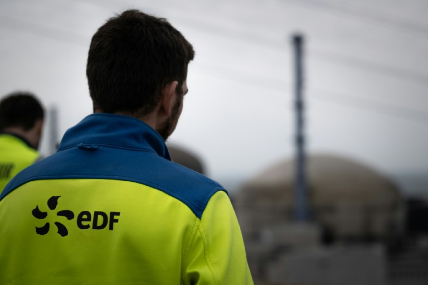 Des employés d'EDF en face d'une coupole de la centrale nucléaire de Flamanville dans la Manche, le 25 avril 2024 © Lou BENOIST