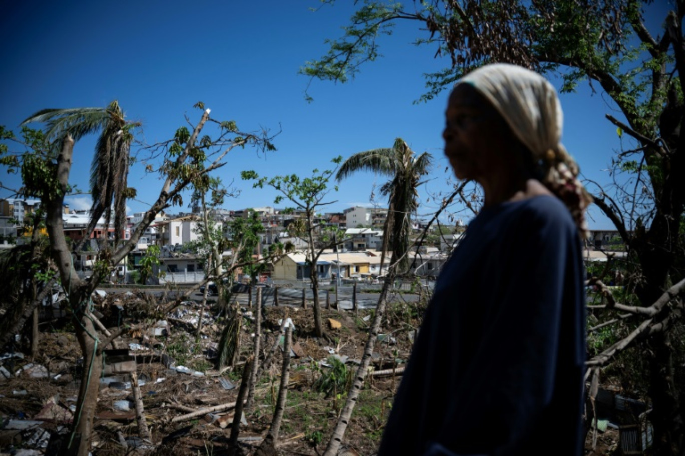 Une femme parmi les maisons détruites d'un bidonville endommagé par le cyclone Chido à Mamoudzou, sur le territoire de Mayotte, le 31 décembre 2024 © JULIEN DE ROSA