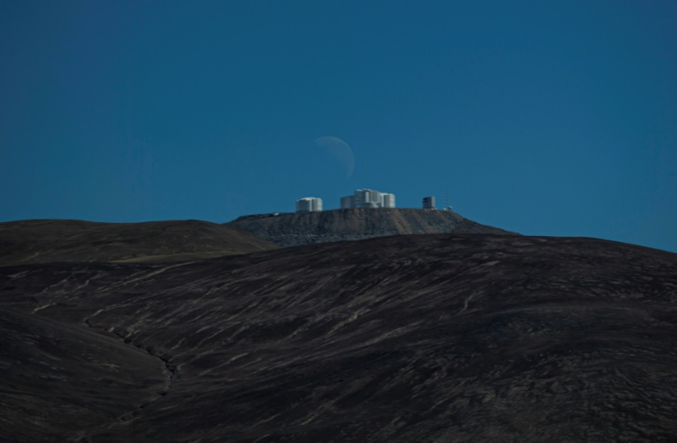 Le dernier quartier de lune se couche derrière la plateforme du Very Large Telescope (VLT), à l'Observatoire européen austral (ESO) de Paranal dans le désert d'Atacama, à environ 1.150 km au nord de Santiago du Chili, le 21 juin 2022 © Martin BERNETTI