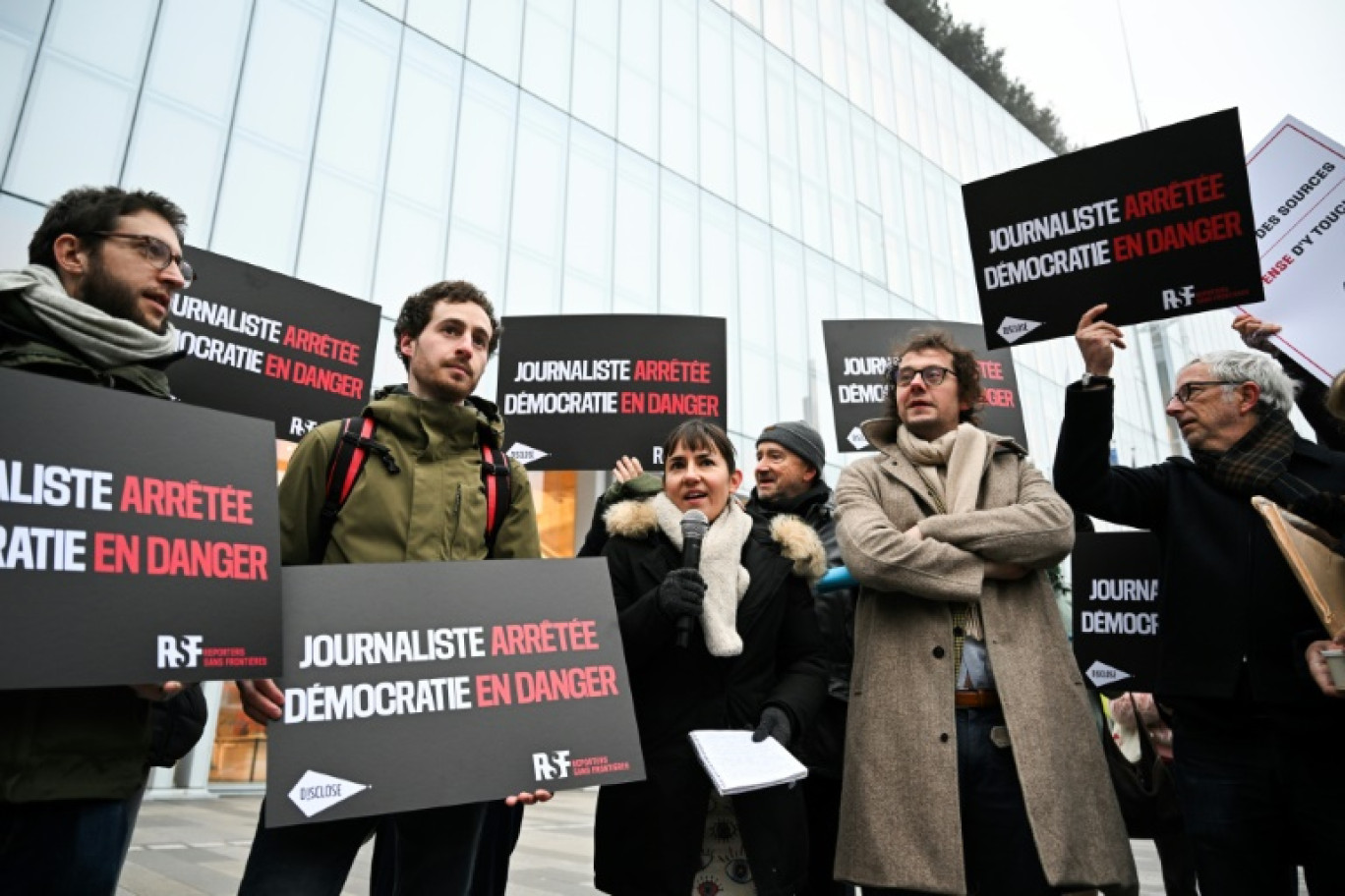 La journaliste française Ariane Lavrilleux (C) prononce un discours à côté du directeur général de Reporters Sans frontières (RSF) Thibaut Bruttin (2D) lors d'un rassemblement de soutien alors qu'elle est convoquée au palais de justice de Paris, le 17 janvier 2025 © Anna KURTH