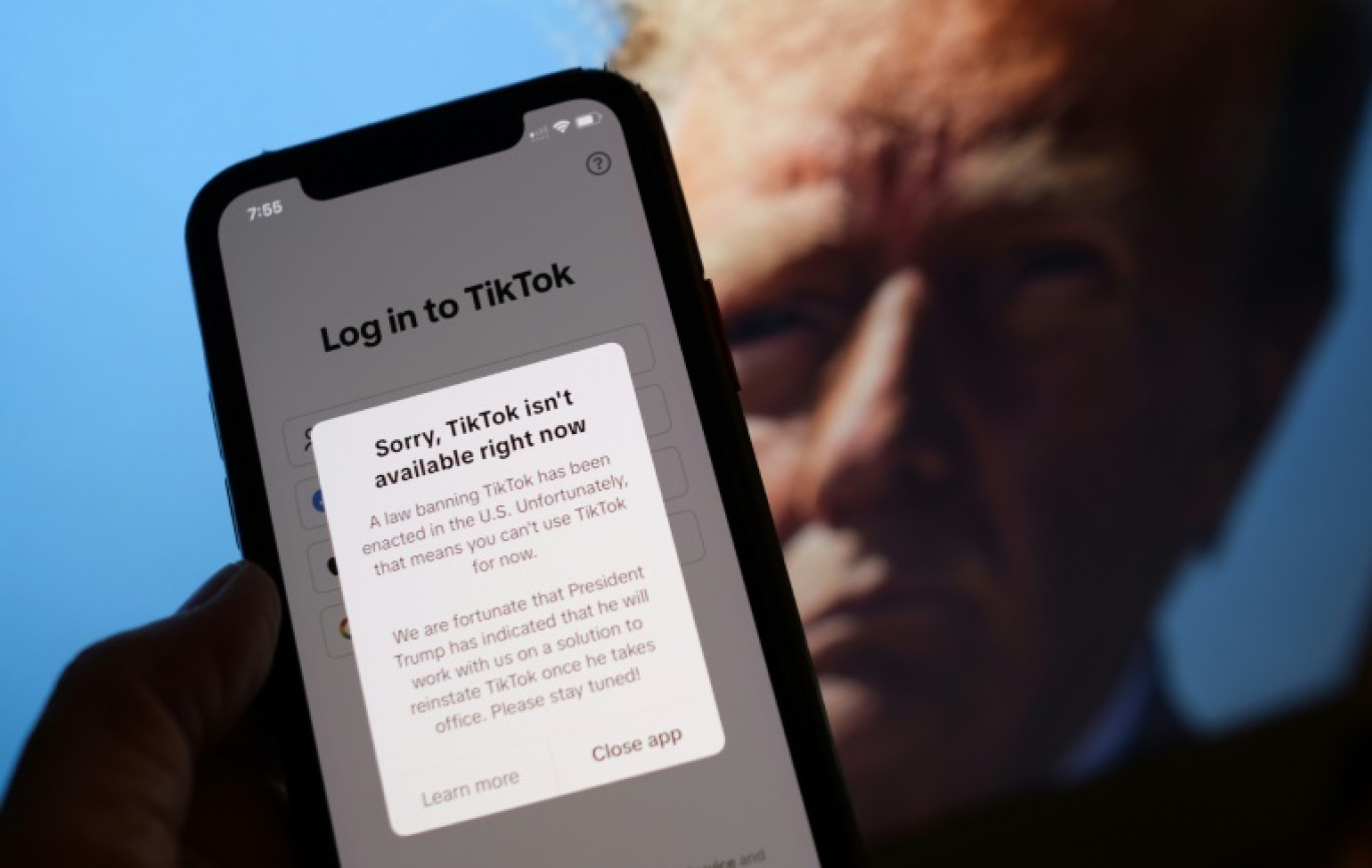 Un téléphone affichant un message en cas de tentative de connexion à TikTok aux Etats-Unis, devant une photo du président américain élu Donald Trump, le 18 janvier 2025 à Washington © Chris DELMAS