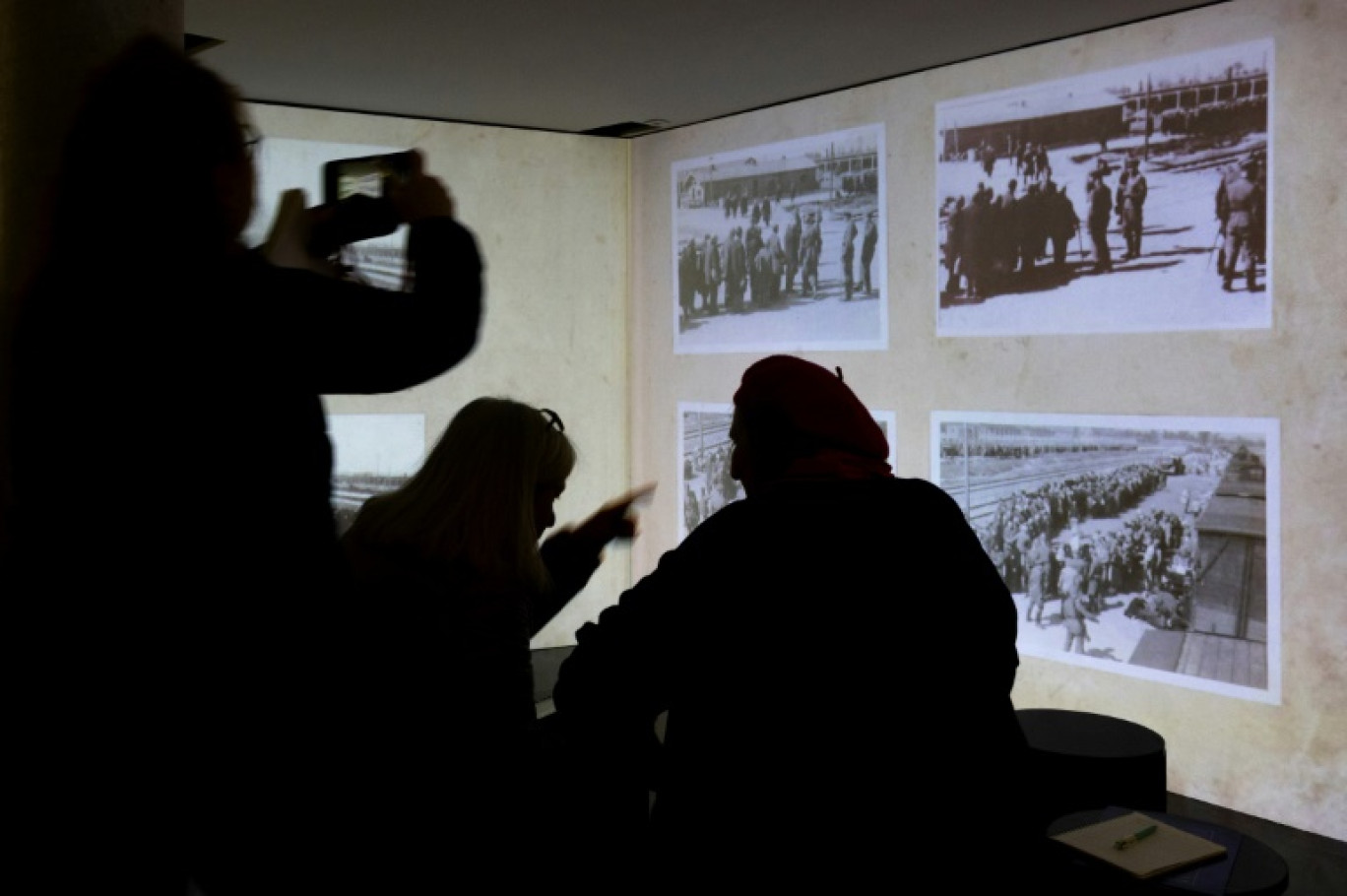 Des visiteurs regardent une installation vidéo contenant des photographies prises par des gardes SS, lors de la visite en avant-première de l'exposition "Comment les nazis ont photographié leurs crimes - Auschwitz 1944" au Mémorial de la Shoah, le 21 janvier 2025 à Paris © Sébastien DUPUY