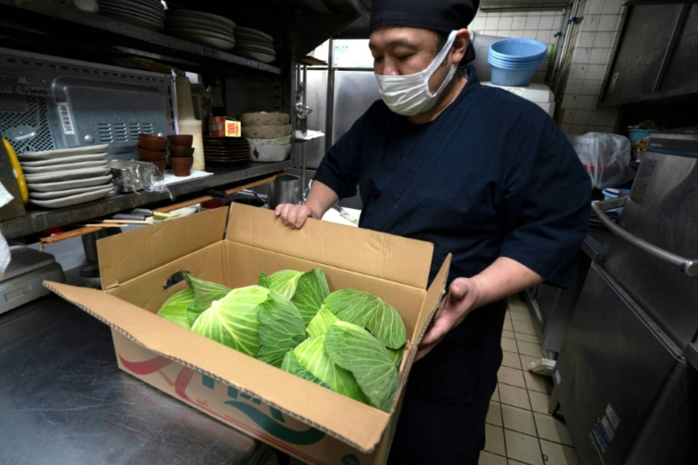 Le chef Katsumi Shinagawa à côté d'un carton de choux qu'il va préparer pour accompagner des escalopes de porc, le 21 janvier 2025 au restaurant Katsukichi à Tokyo © Kazuhiro NOGI