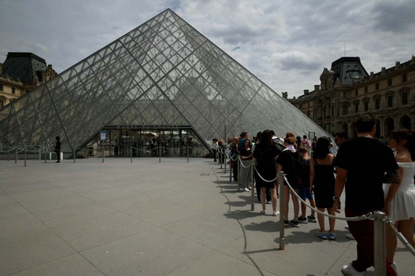 Des visiteurs font la queue devant la pyramide de l'architecteIeoh Ming Pei au musée du Louvre à Paris, le 11 juillet 2024 © EMMANUEL DUNAND