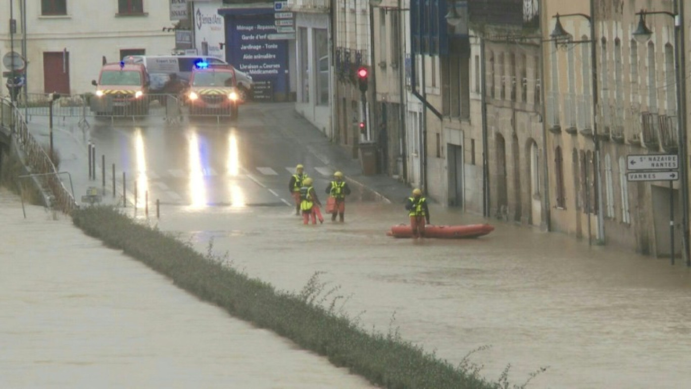 Un homme marche sur des planches surélevées pour circuler dans une rue inondée de Redon, le 30 janvier 2025, en Ille-et-Vilaine © JEAN-FRANCOIS MONIER