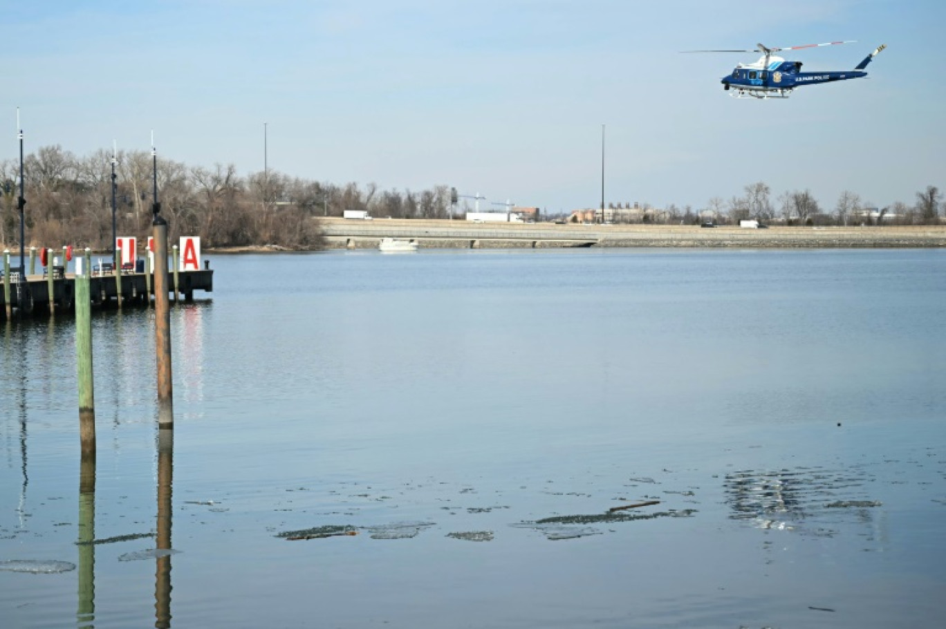 Un hélicoptère de la police survole la rivière Potomac près de l'aéroport Ronald-Reagan à Washington, où les secours tentent de retrouver les corps des victimes de la collision entre un avion civil et un hélicoptère militaire, le 30 janvier 2025 © ANDREW CABALLERO-REYNOLDS