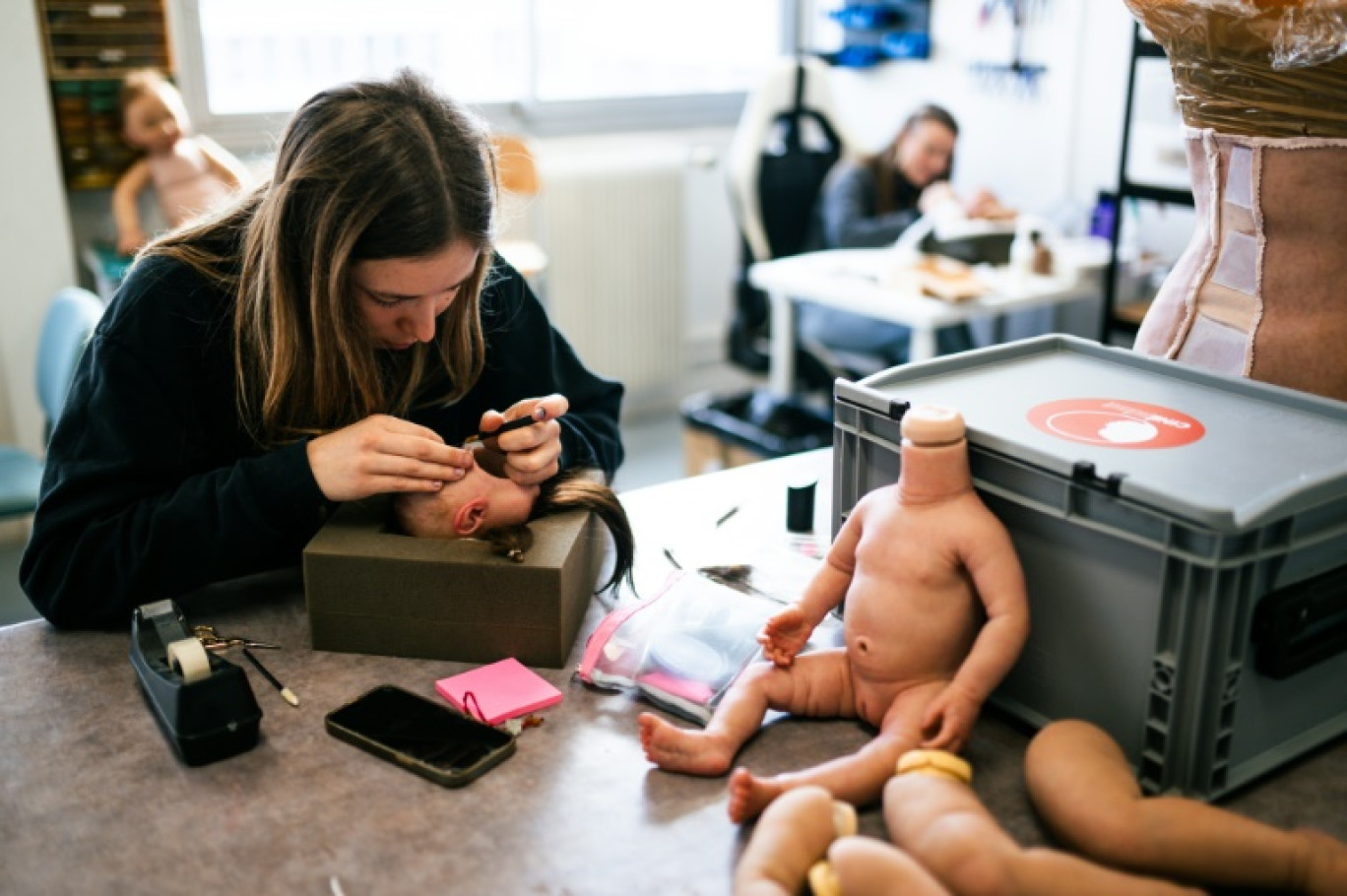 Une technicienne d'atelier implante de la laine pour simuler une chevelure sur de faux bébés en silicone dans les locaux de l'entreprise Cinébébé, le 27 janvier 2025 à Saint-Denis, près de Paris © Julie SEBADELHA