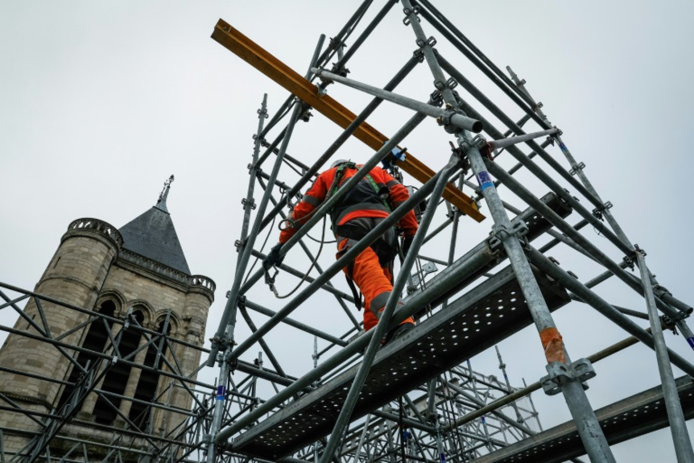 Un employé travaille sur la façade de la cathédrale de Saint-Denis pendant les travaux de reconstruction de la flèche, le 4 février 2025 près de Paris © GEOFFROY VAN DER HASSELT