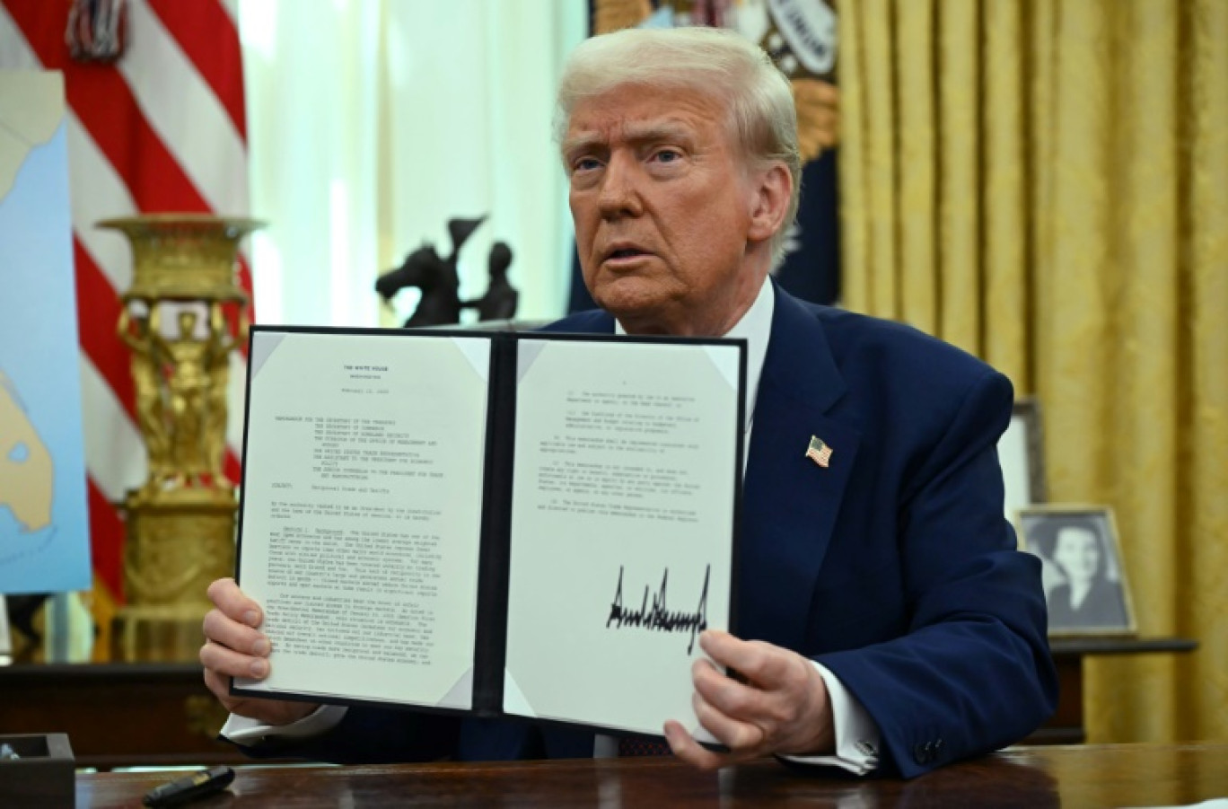 Le président américain Donald Trump montre le décret qu'il vient de signer sur les "droits de douane réciproques" dans le Bureau ovale de la Maison Blanche, le 13 février 2025 à Washington © ANDREW CABALLERO-REYNOLDS