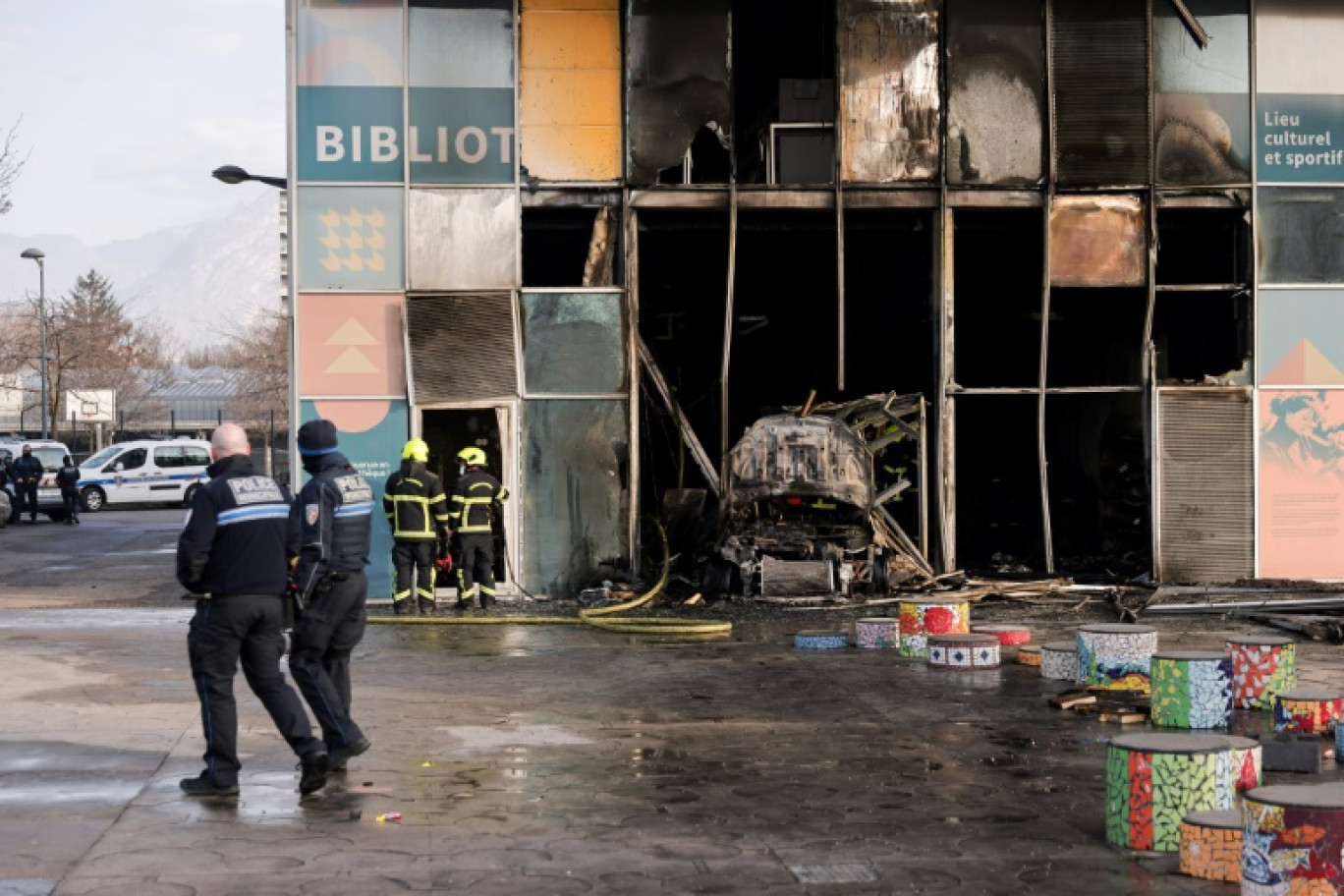 Des pompiers et des policiers devant une bibliothèque incendiée à Grenoble par une voiture-bélier en feu, le 19 février 2025 © Maxime GRUSS