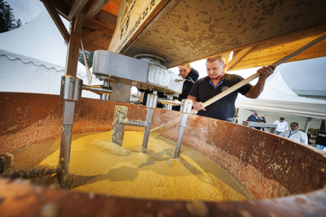 Un homme mélange le fromage et le vin à l'aide d'une spatule géante alors que le fromager JuraFlore tente de battre le record du monde Guinness de la plus grande fondue au fromage, au "Fort des Rousses", le 22 février 2025 dans le Jura © Valentin FLAURAUD