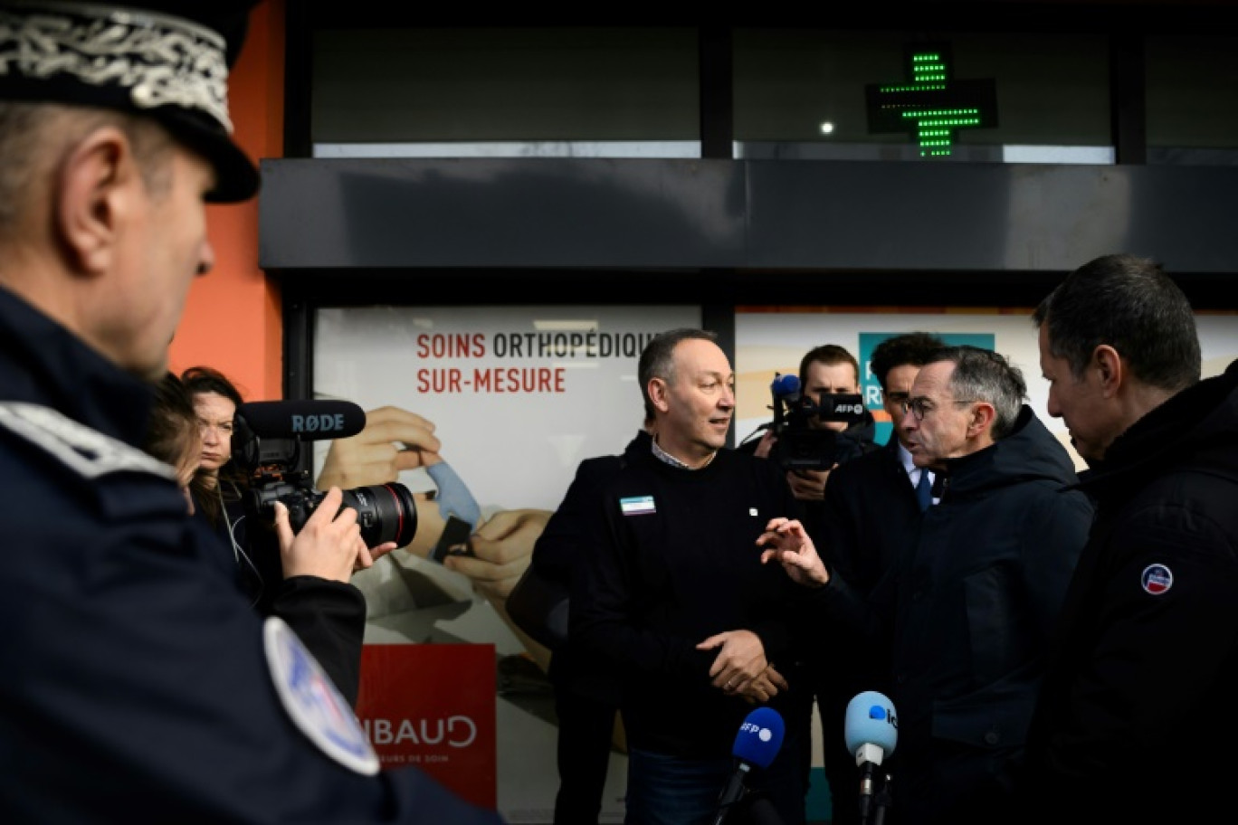 Le ministre de l'Intérieur Bruno Retailleau (de profil à droite) discute avec un pharmacien (au centre) lors d'une visite du quartier de Fontbarlettes, à Valence, le 21 février 2025 © JEFF PACHOUD