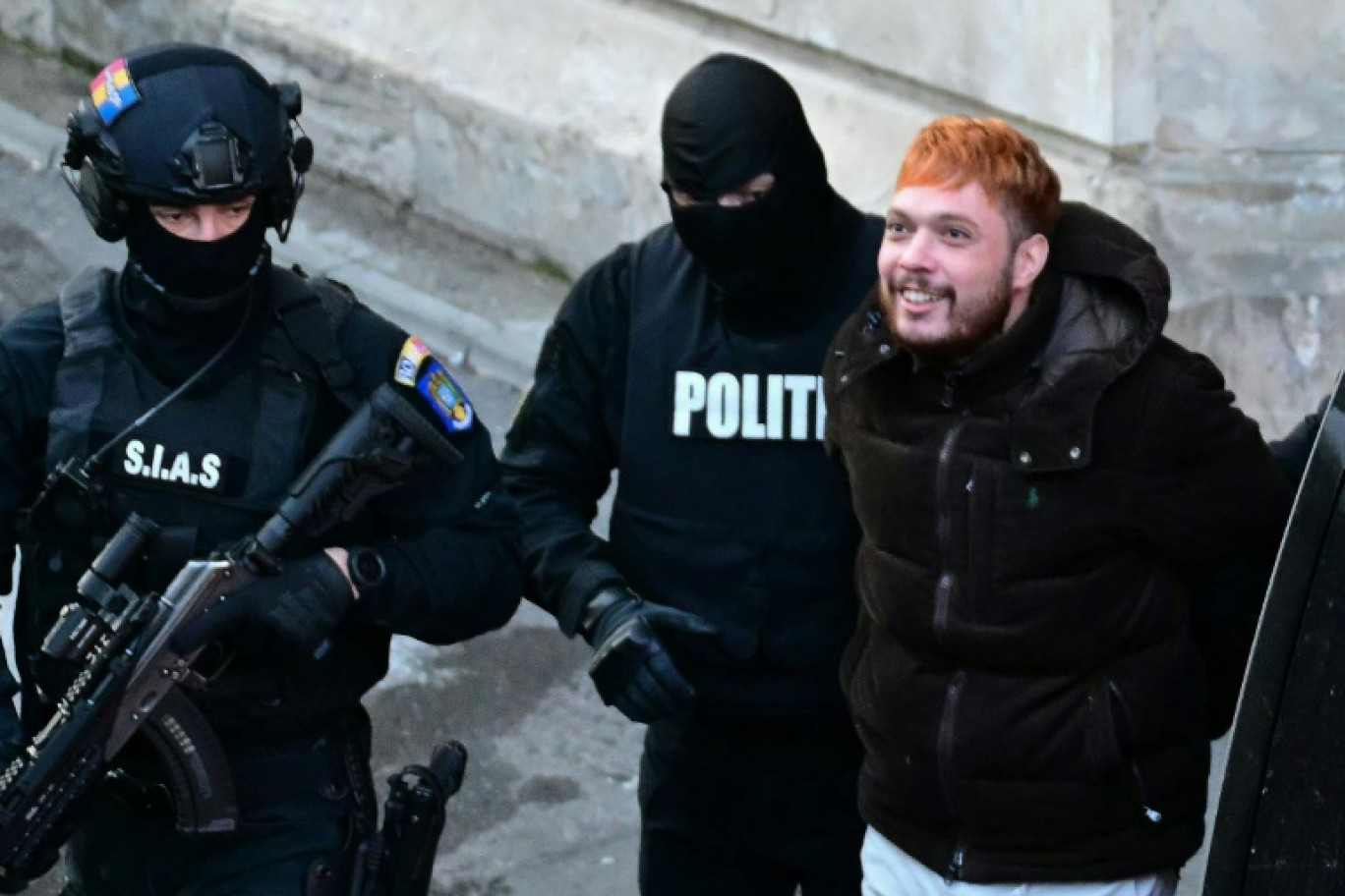 Le trafiquant de drogue français Mohamed Amra (c) escorté par des policiers hors de la Cour d'appel de Bucarest, le 23 février 2025, au lendemain de son arrestation en Roumanie © Daniel MIHAILESCU