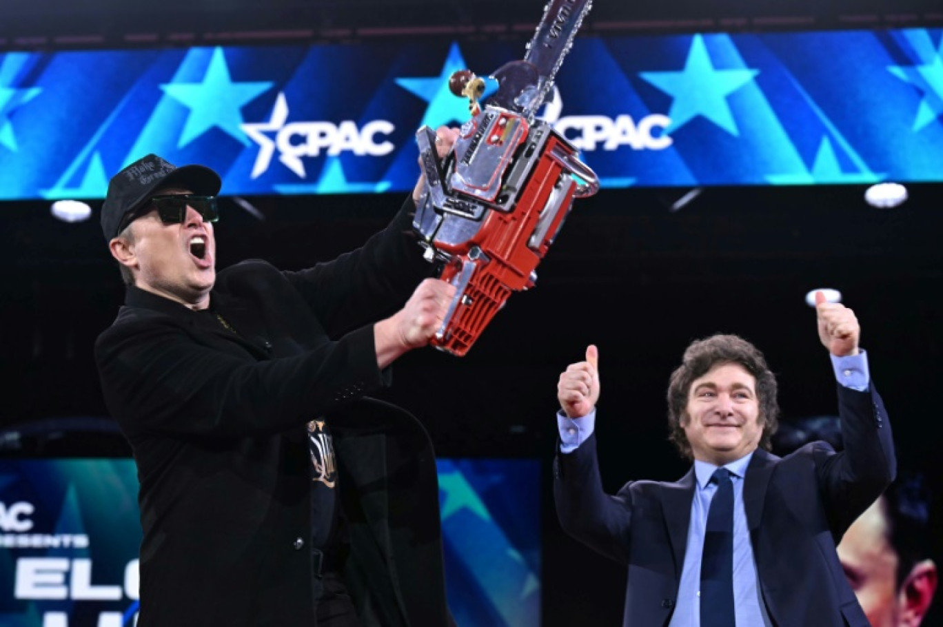 Elon Musk brandit une tronçonneuse aux côtés du président argentin Javier Milei au cours de la grand messe du Parti républicain CPAC à Oxon Hill (Maryland, Etats-Unis) le 20 février 2025 © SAUL LOEB