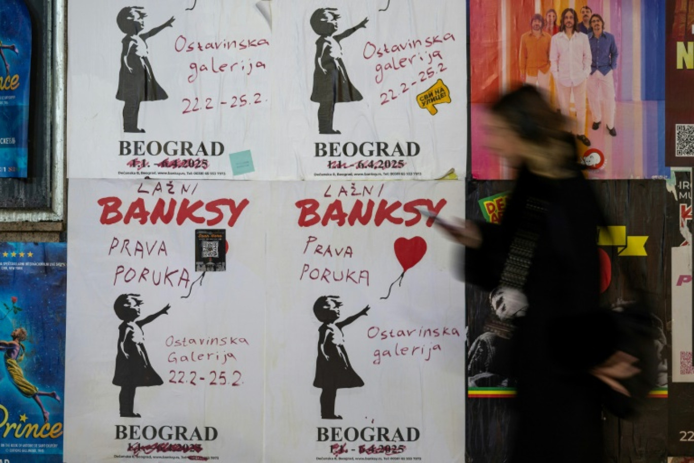 Une femme passe près de l'affiche d'une exposition Banksy à Belgrade, le 25 février 2025 © Andrej ISAKOVIC