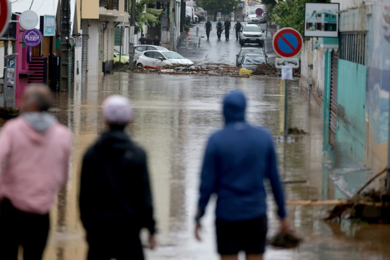 Des piétons et des de la gendarmes sur une route inondée à Saint-Paul de La Réunion, le 28 février 2025 © Richard BOUHET