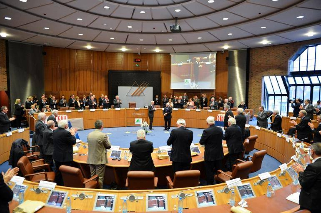 Sous des applaudissements unanimes, l'actuel président michel Dagbert félicite le président honoraire Dominique Dupilet au centre de l'hémicycle du conseil général.