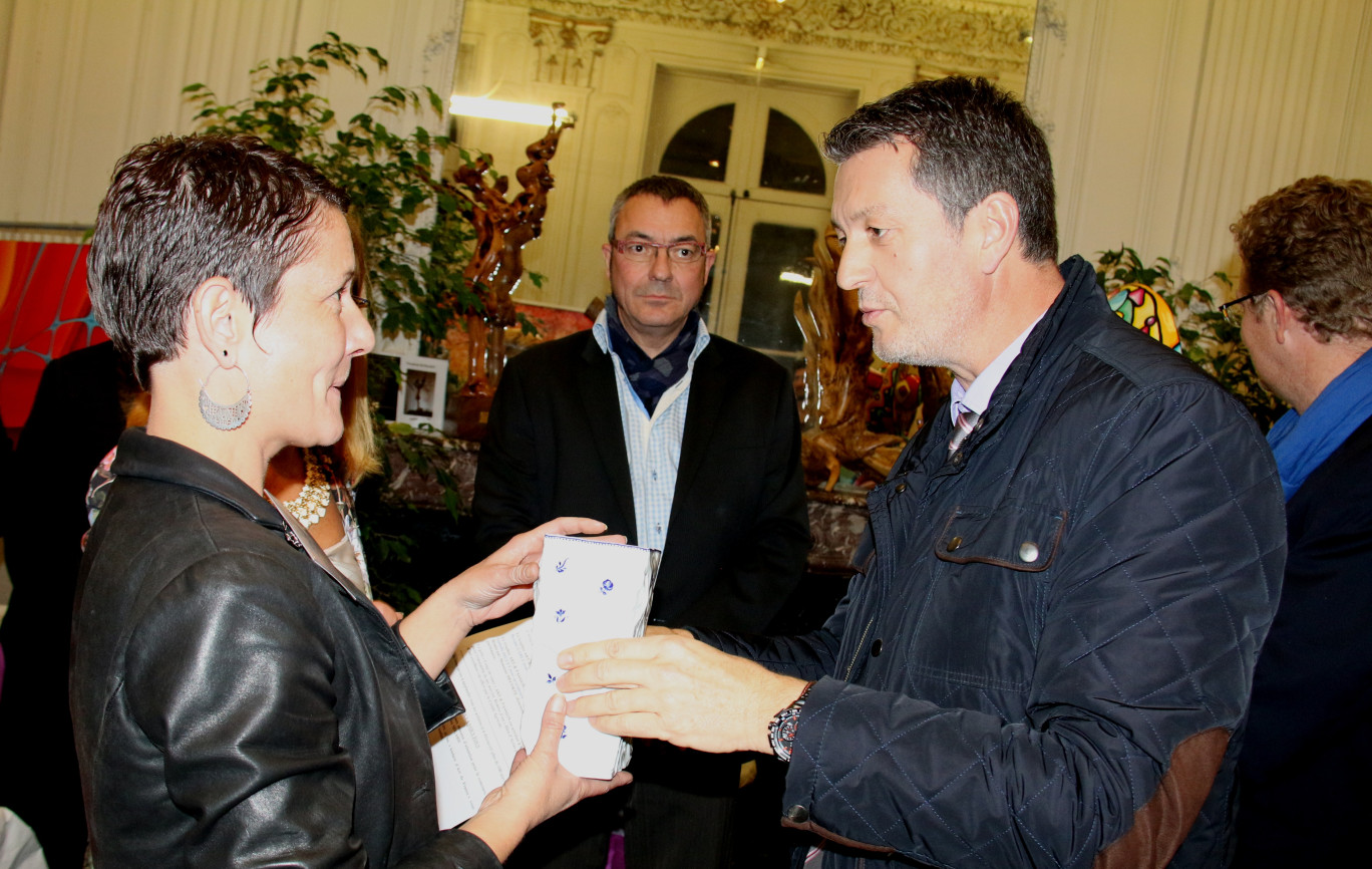 Eric Lorber, directeur du secteur Artois au Crédit Agricole Nord de France, offre une porcelaine d’Arras à Isabelle Diguet en présence de Maurice Ségard en arrière plan (artisan décorateur sur porcelaine qui perpétue la tradition du bleu d’Arras).